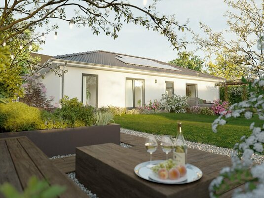 Massiv gebauter Bungalow ERA 131 mit bodentiefen Fenstern, Photovoltaikanlage und überdachter Terrasse bei Sonnenuntergang