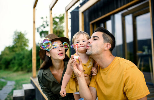 Junge Familie mit kleiner Tochter im Freien, Wochenende in einem Minihaus auf dem Lande.