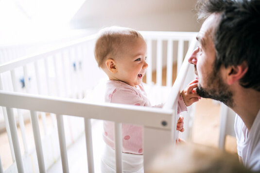 Kind im Babybett mit Papa