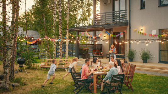 Große Familie sitzt im Garten beim Barbeque.