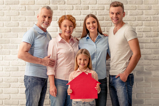 Glückliche Familie steht vor einer Wand und freut sicht.