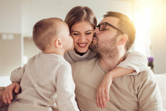 Vater und Sohn küssen Mutter