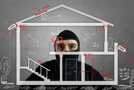Einbrecher hinter einer Hausgrafik