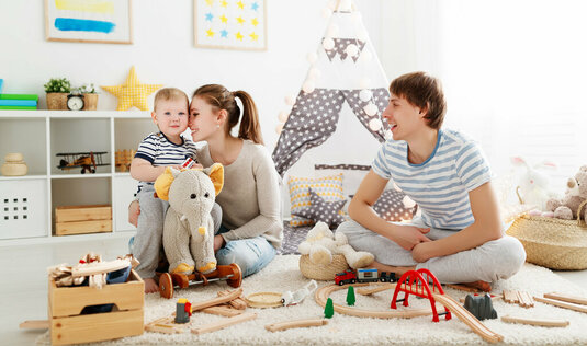 Mutter Vater und Kind spielen zusammen im Kinderzimmer.