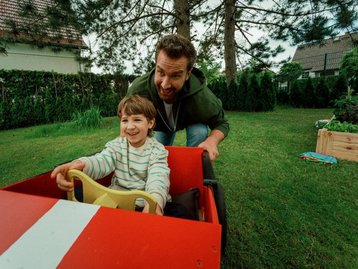Sorgloser Familienmoment mit Seifenkiste – Symbol für ganzheitliche Hausbau-Begleitung