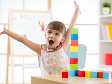 Traumhaus gesichert durch Schutz nach dem Bau Mädchen freut sich über hohen Baustein Turm und zeigt Schutz nach Bau durch Gewährleistungsbürgschaft sowie 20 Jahre Notfallplan